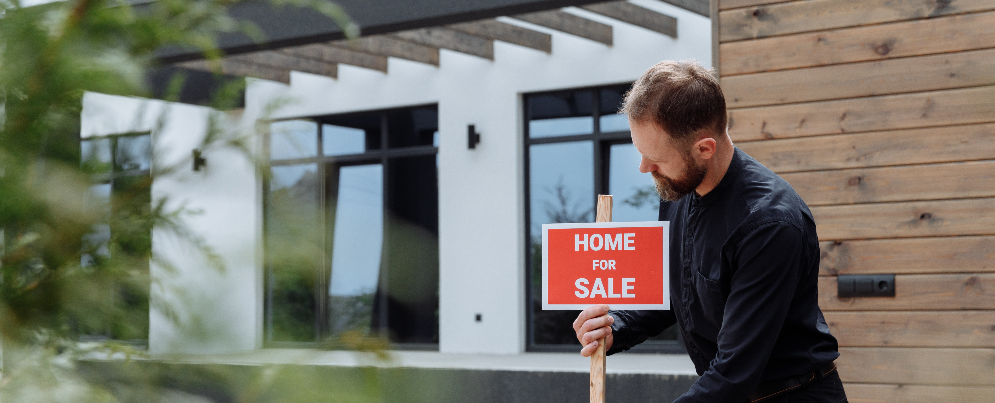 man with home sale board