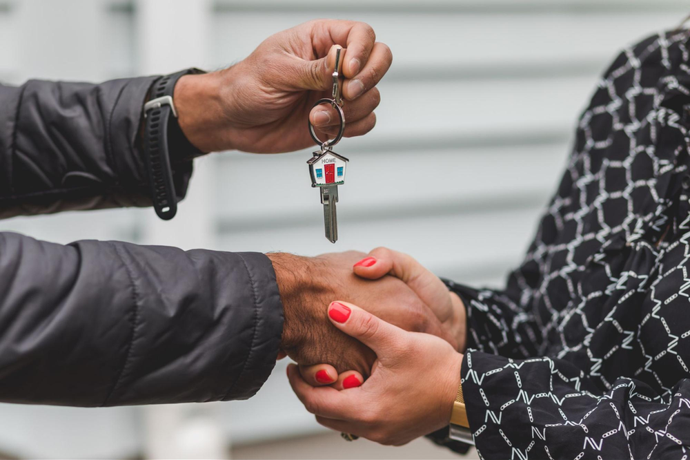 man holding a woman's hand with home key